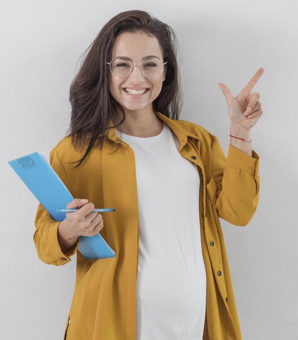 smiley pregnant woman holding clipboard pointing up with copy space